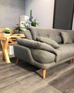 a grey couch sitting on top of a hard wood floor next to a wooden table