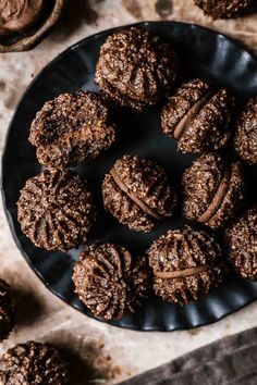 chocolate cookies on a black plate next to some cups