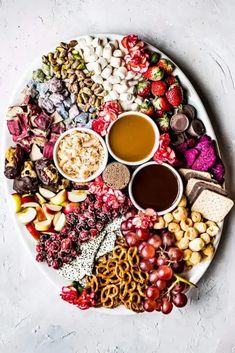 a white plate topped with lots of different types of snacks and dips on top of each other