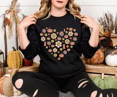 "Embrace the cozy charm of autumn with our Retro Fall Season Sweatshirt, featuring a beautifully crafted heart of autumn design and delicate autumn flowers--perfect for adding a touch of nostalgia to your fall wardrobe." Are you looking for (Retro Season Sweatshirt)? We got you! ✅ ABOUT OUR (Retro Fall Season Sweatshirt) Crewneck ▸These garments are made from polyester and cotton.  ▸The collar is ribbed knit, so it retains its shape even after washing.  ▸ There are no itchy side seams on these s Long Sleeve Heart Graphic Sweater For Fall, Fall Long Sleeve Top With Heart Graphic, Long Sleeve Sweatshirt For Fall Gift, Crew Neck Sweater As Fall Gift, Crew Neck Sweater For Fall - Great As Gift, Retro Heart, Flower Sweatshirt, Autumn Design, Autumn Flowers