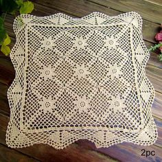 a white doily sitting on top of a wooden table next to flowers and leaves