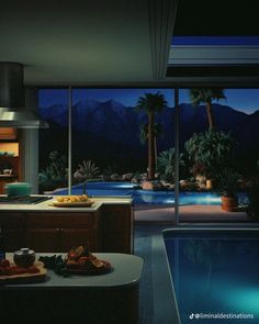 a kitchen with a pool and mountains in the background at night, as seen from an indoor swimming pool