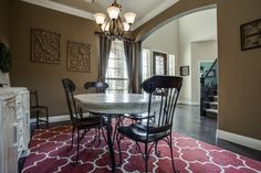 a dining room table with four chairs and a red rug in front of the fireplace