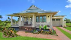 a house that is in the middle of some grass and flowers on the front lawn