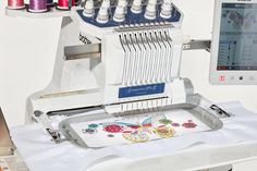 an embroidery machine is on the table next to some thread