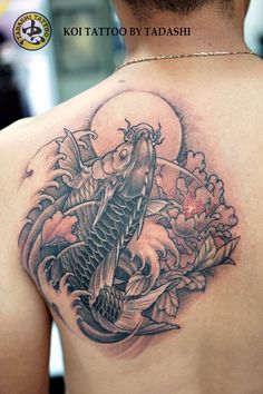 the back of a woman's shoulder with a koi fish tattoo on it