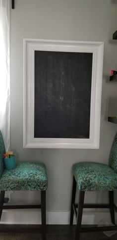 two green chairs sitting in front of a chalkboard with a blackboard on it