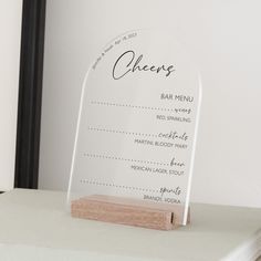 a clear acrylic sign sitting on top of a white counter next to a mirror