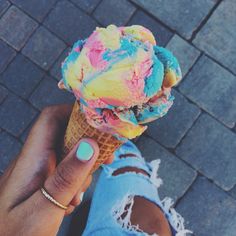 a person holding an ice cream cone with colorful toppings