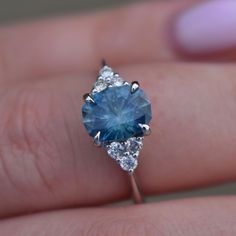 a woman's hand holding a blue and white diamond ring