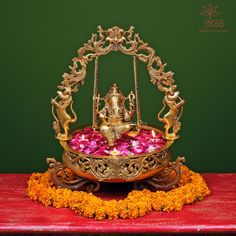 a gold plate with flowers on it and a ganeshi idol in the middle