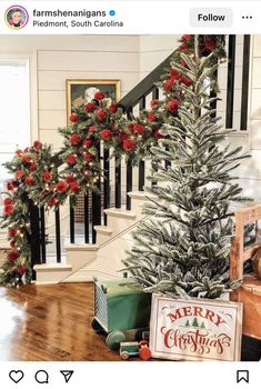 a christmas tree with red flowers and greenery on it in front of a staircase