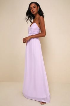 a woman in a strapless lilac dress poses for the camera with her hand on her hip