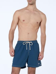 Introducing our Patmos swim shorts, crafted from textured polyester fabric, offering a cotton-like touch. Enhanced with contrast stitching and drawstring, as well as the embroidered exclusive Saint Barth logo detail at the bottom leg. Features a back pocket with flap and velcro closure. This version is made from fast-drying seersucker fabric with a vertical pinstripe pattern. Man Patmos mid-length swim shortsFast dry seersucker fabricSky blue plain colorExclusive Saint Barth logo detail at the bottom legComfortable elasticized waistbandAdjustable drawcord with branded terminalsInner mesh liningSide pockets with French seamsBack patch pocket with velcro closureBranded eyelets designed to drain water and prevent ballooning effectMC2 Saint Barth exclusive label on the backClassic fitCompositi Blue Bottoms With Contrast Stitching For Summer, Blue Shorts With Functional Drawstring, Summer Bottoms With Contrast Stitching In Short Length, Summer Bottoms With Contrast Stitching And Short Length, Navy Drawstring Shorts, Navy Drawstring Bottoms Short Length, Summer Shorts With Contrast Stitching, Blue Nylon Swim Trunks With Functional Drawstring, Blue Nylon Beachwear Bottoms