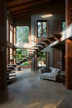 a living room filled with lots of furniture next to a stair case in front of a window