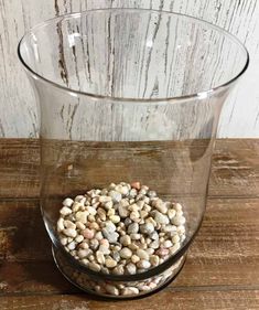 a glass vase filled with rocks on top of a wooden table