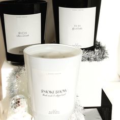 three wine bottles sitting next to each other on top of a white table with silver tinsel