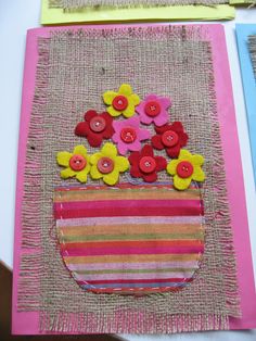 a piece of fabric with buttons and flowers in a vase on top of some burlap