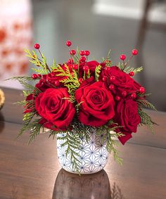 a vase filled with red roses on top of a wooden table