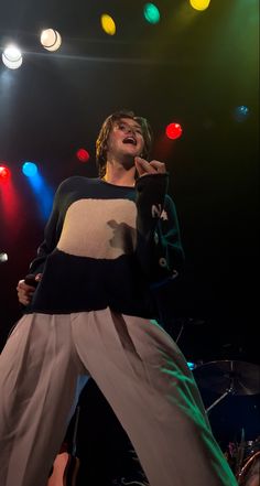 a woman standing on top of a stage with her hands in the air while singing