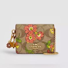 Brand New With The Tags And Absolutely Gorgeous Describes This Authentic Coach Mini Wallet On A Chain In Signature Canvas With Floral Print. Measurements: Length: 4.0" Height: 3.0" Width: 1.0" Materials: Signature Coated Canvas And Smooth Leather Fabric Lining Strap Detachable Chain Strap With 23.25" Drop Features: Outside Open Pocket Snap Closure Two Credit Card Slots Doesn’t Include Charms. Coach Mini Wallet, Signature Canvas, Mini Wallet, Leather Fabric, Chain Strap, Smooth Leather, Coach Bags, Snap Closure, Card Slots