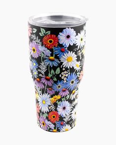 a black and white floral tumbler cup with colorful daisies on it's side