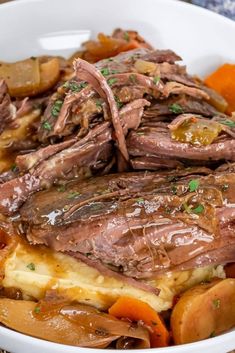 a white bowl filled with meat, potatoes and carrots on top of a table