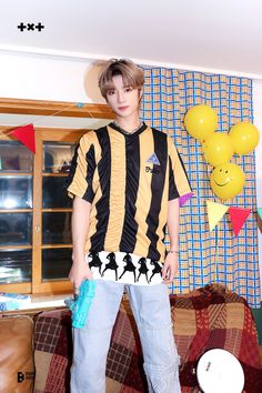 a young man standing on top of a couch in a living room next to balloons