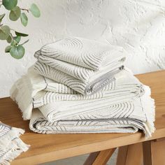 a stack of towels sitting on top of a wooden table next to a potted plant