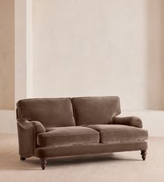 a brown couch sitting on top of a hard wood floor next to a white wall