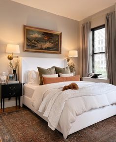 a large bed sitting in a bedroom next to two lamps and a painting on the wall