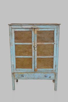 an old blue cabinet with glass doors on the top and bottom, against a gray background