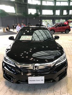 a black honda car is on display in a showroom