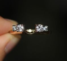 a person is holding a diamond ring in their left hand and it has three stones on the side