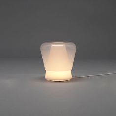 a white light sitting on top of a table next to a gray wall and floor