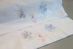 two white sheets with blue and pink flowers on them