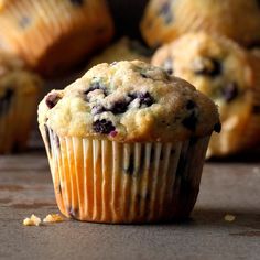 a muffin with blueberries and crumbs sitting on a table next to other muffins