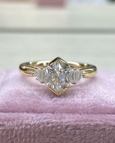 a three stone diamond ring sitting on top of a pink towel