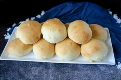 a white plate topped with rolls on top of a blue cloth