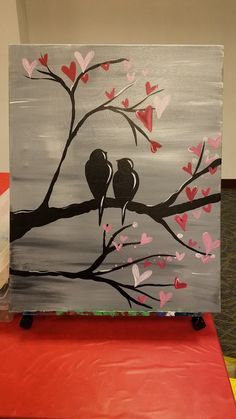 two birds sitting on a branch with hearts painted on it