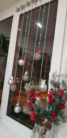 a vase filled with christmas decorations and ornaments hanging from the side of a window sill