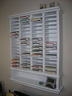 a white book shelf filled with lots of books next to a wall mounted electronic device