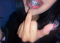 a woman with piercings on her fingers is holding a metal object in front of her mouth