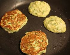 three crab cakes cooking in a pan with some sauce on the top and one being cooked