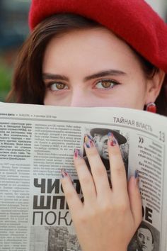 a woman reading a newspaper with her hands on the front page