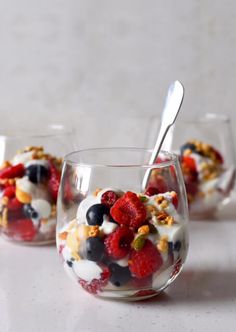 three glasses filled with fruit and yogurt on top of a white countertop