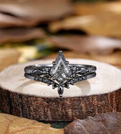 a diamond ring sitting on top of a piece of wood with leaves in the background