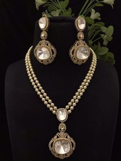 a necklace and earring set on a mannequin with flowers in the background