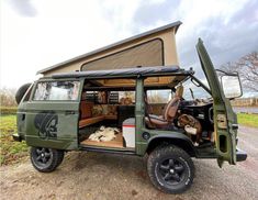 an army green jeep with the doors open and two dogs sleeping in it's bed