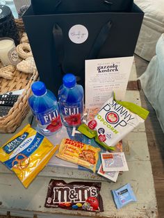 an assortment of snacks and drinks sitting on a coffee table next to a shopping bag